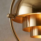 Close detail of the lit Clérachic floor lamp in Brass, its brushed shades and the fixed inner cylinders they turn around.
