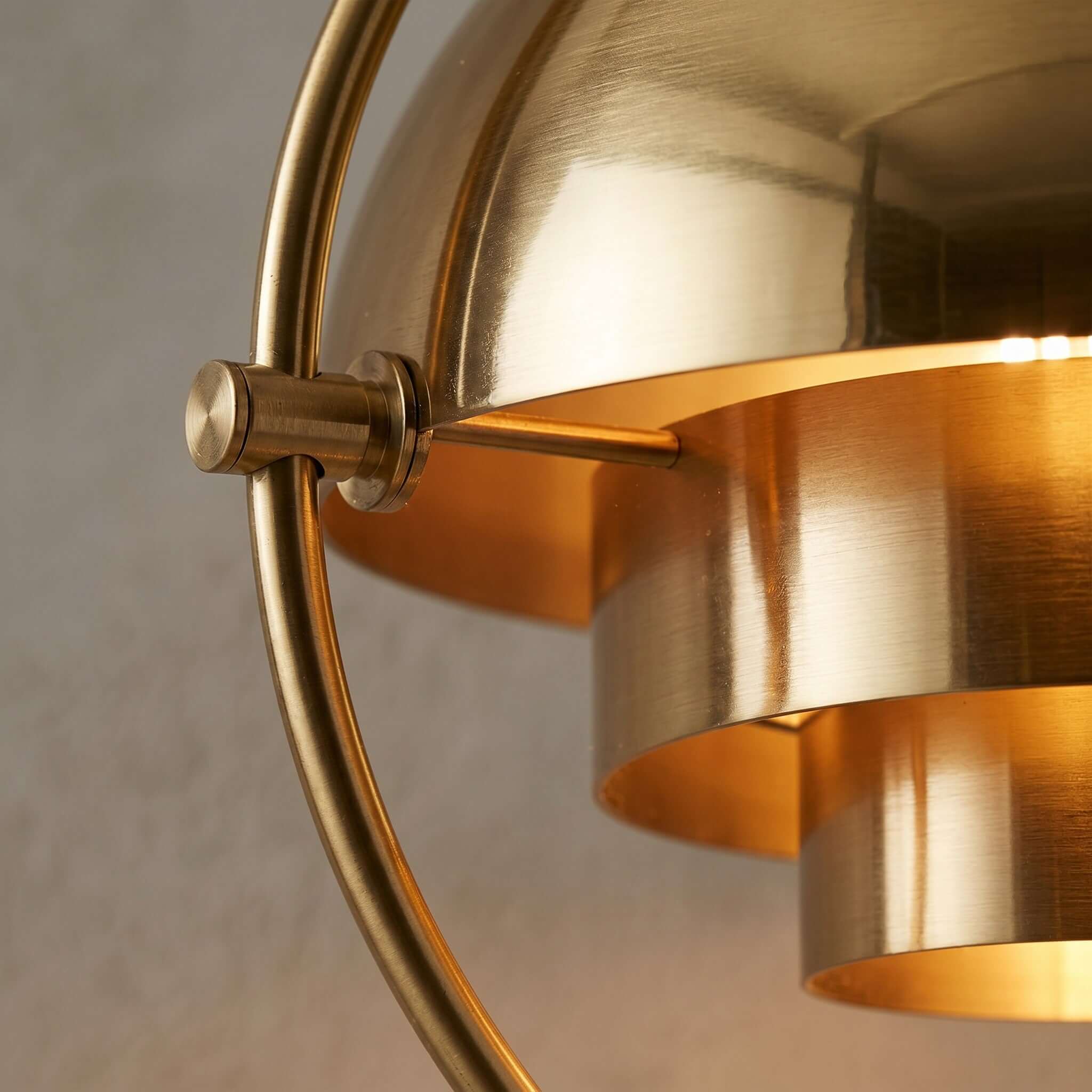 Close detail of the lit Clérachic floor lamp in Brass, its brushed shades and the fixed inner cylinders they turn around.