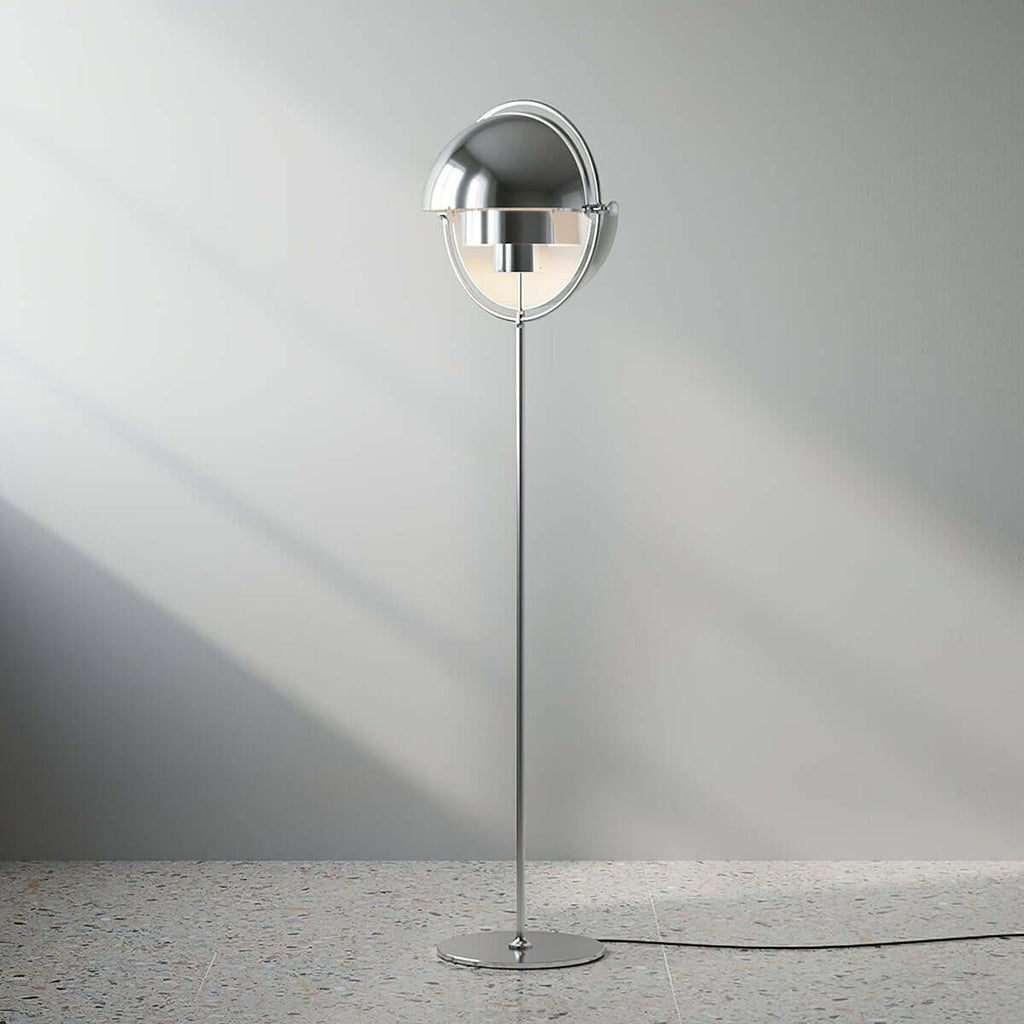 Casting a soft shadow on a pale wall, the lit Clérachic floor lamp in Chrome shows its polished shades and slim stem.