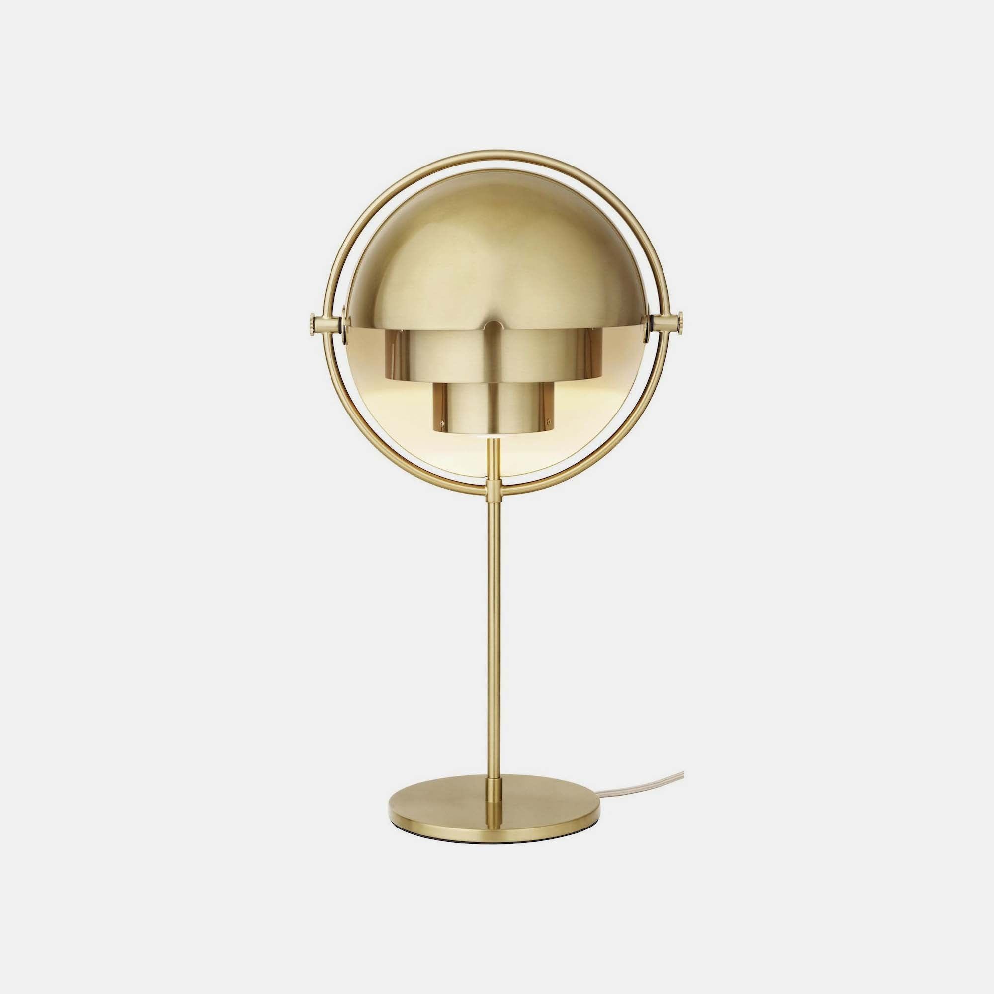 The Clérachic table lamp in Brass, brushed across shades, ring, stem and base, with its textile mains cord trailing from the round base.