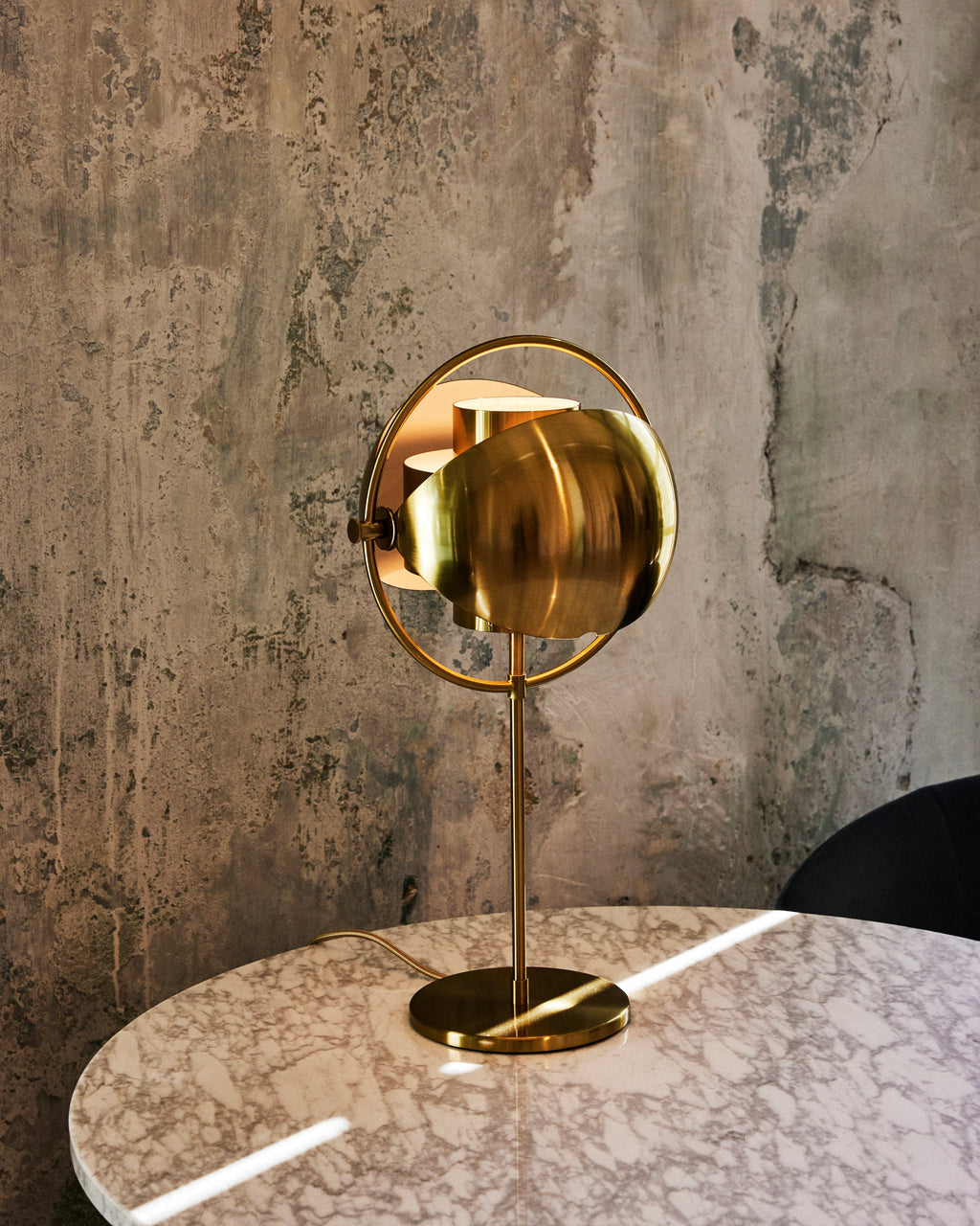 Clérachic's Brass table lamp on a marble table against a weathered concrete wall, bringing a soft metallic warmth to a pared-back corner.
