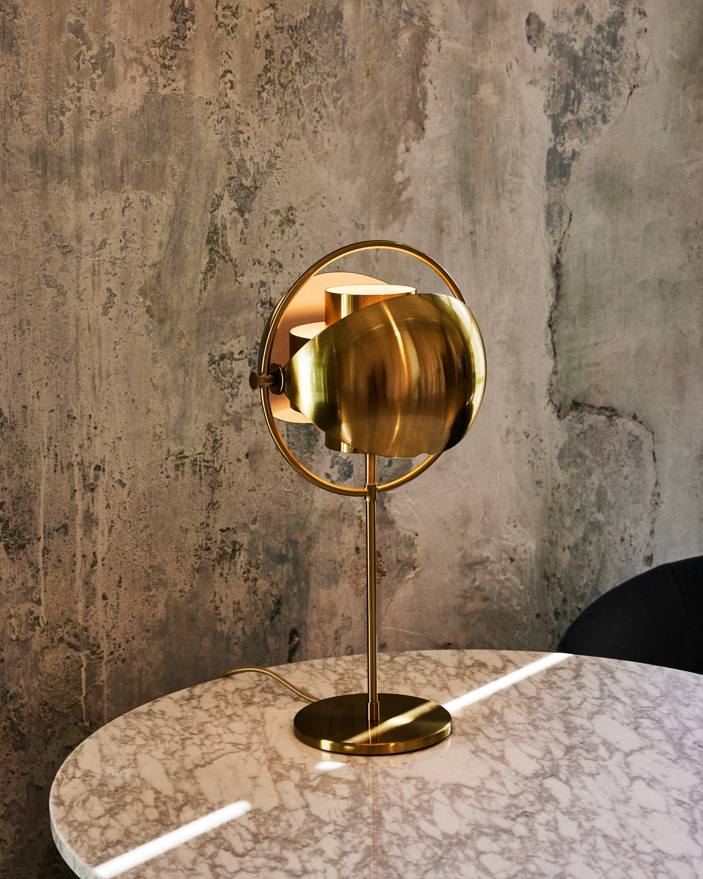 Clérachic's Brass table lamp on a marble table against a weathered concrete wall, bringing a soft metallic warmth to a pared-back corner.