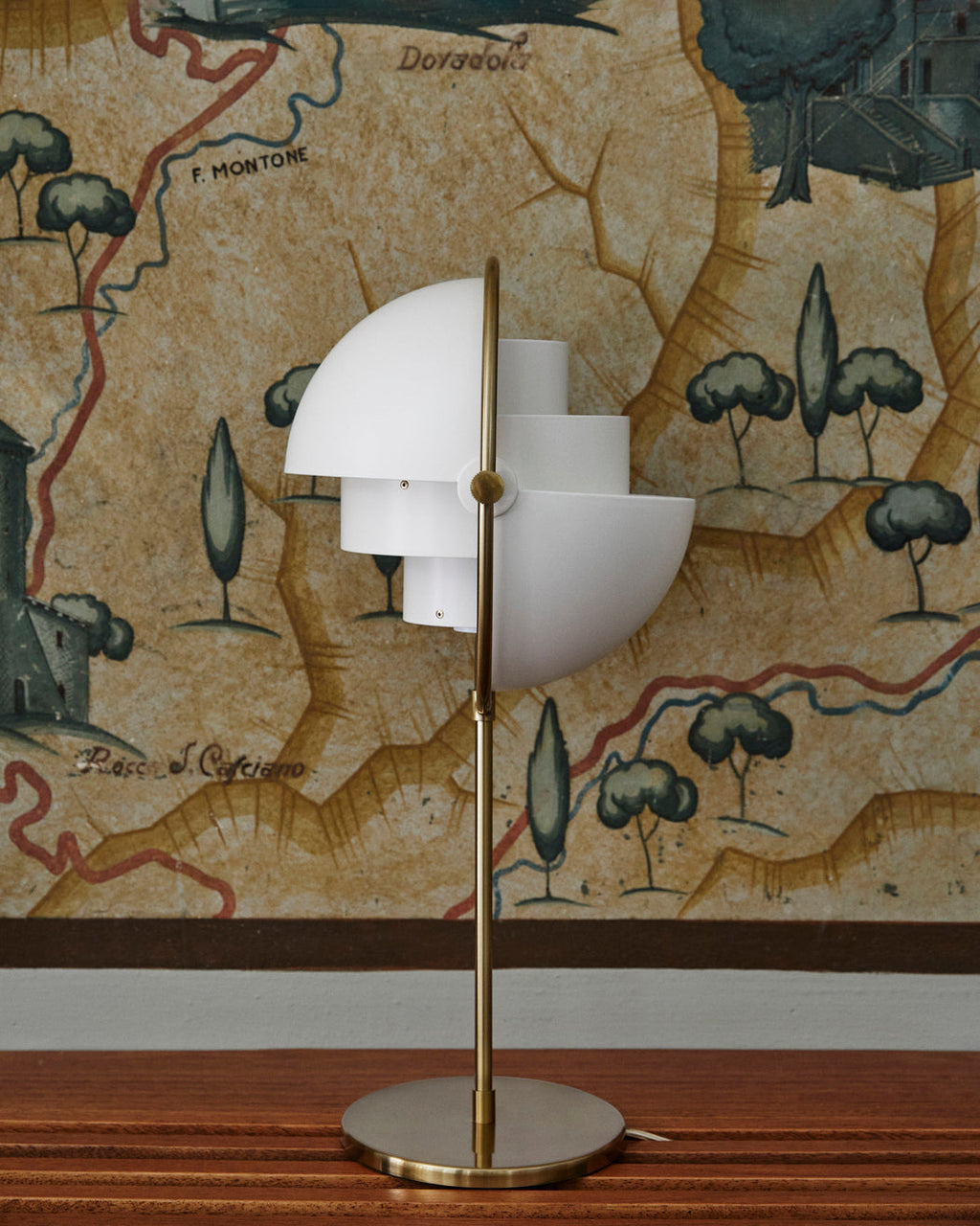 Styled against a painted antique map mural, the Clérachic table lamp in White & Brass pairs gloss white shades with a brushed brass ring and stem.