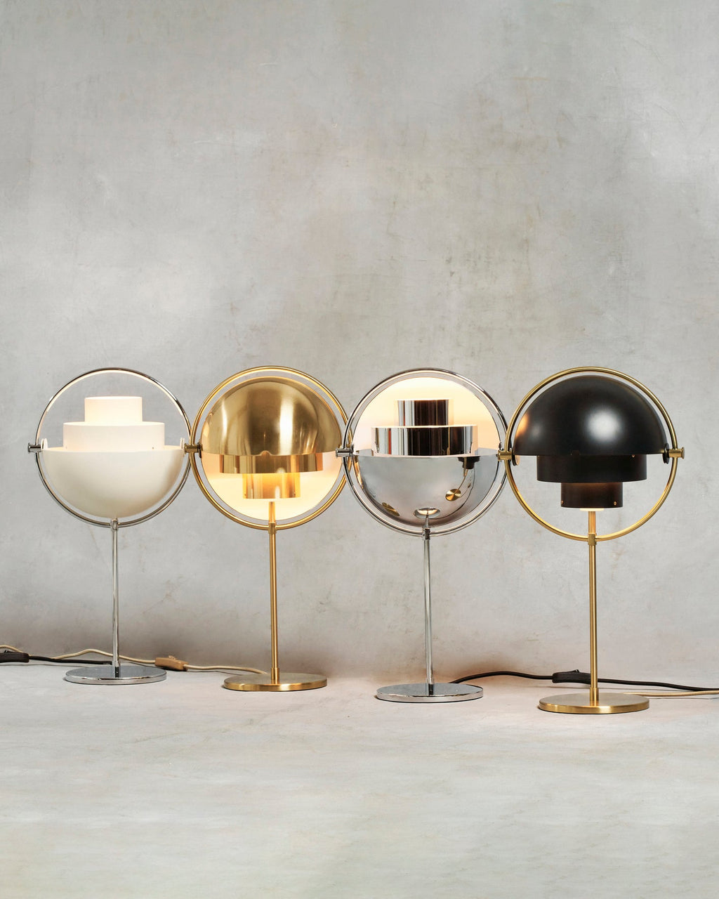 Four lit Clérachic table lamps lined up together — White & Chrome, Brass, Chrome and Black & Brass — showing how each finish handles the light.