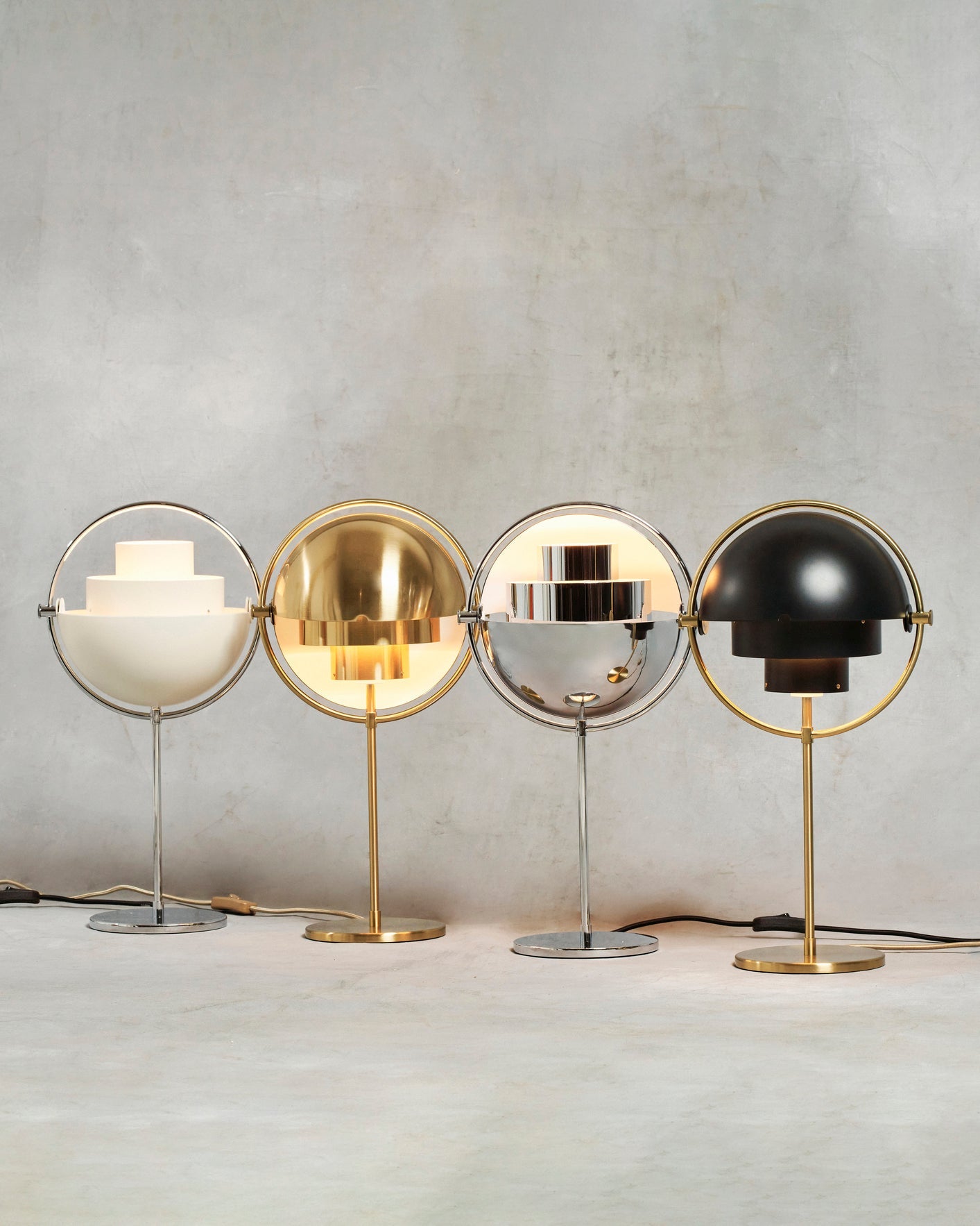 Four lit Clérachic table lamps lined up together — White & Chrome, Brass, Chrome and Black & Brass — showing how each finish handles the light.