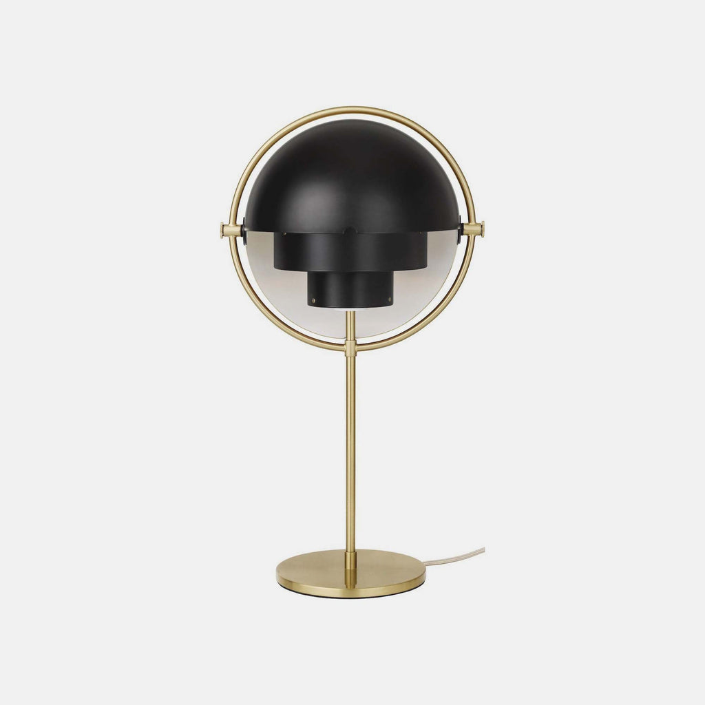 Photographed on a plain backdrop, the Clérachic table lamp in Black & Brass sets matt black shades against a brushed brass ring, stem and base.