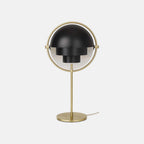 Photographed on a plain backdrop, the Clérachic table lamp in Black & Brass sets matt black shades against a brushed brass ring, stem and base.