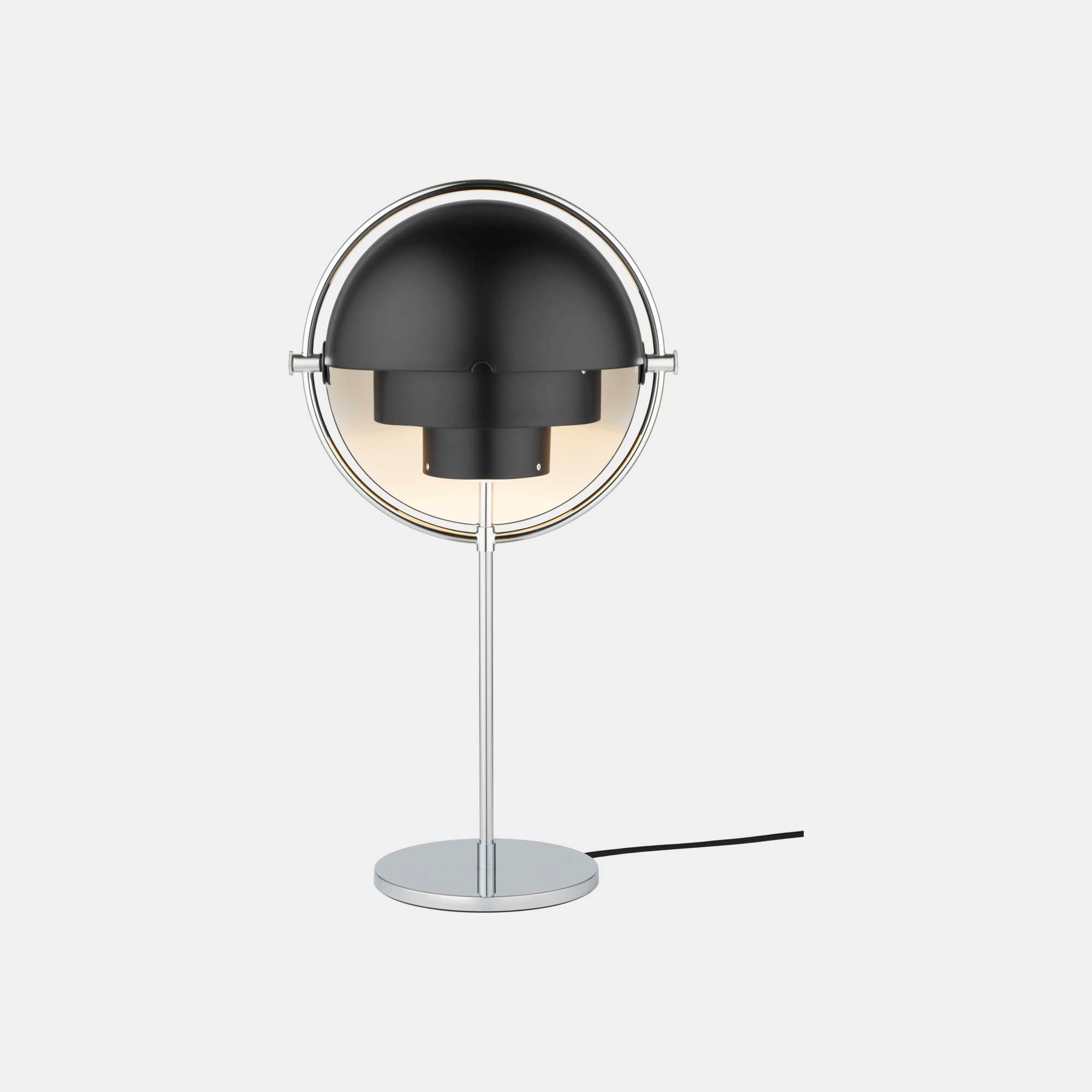 Lit on a plain backdrop, the Clérachic table lamp in Black & Chrome casts a soft pool of light down from between its matt black shades.