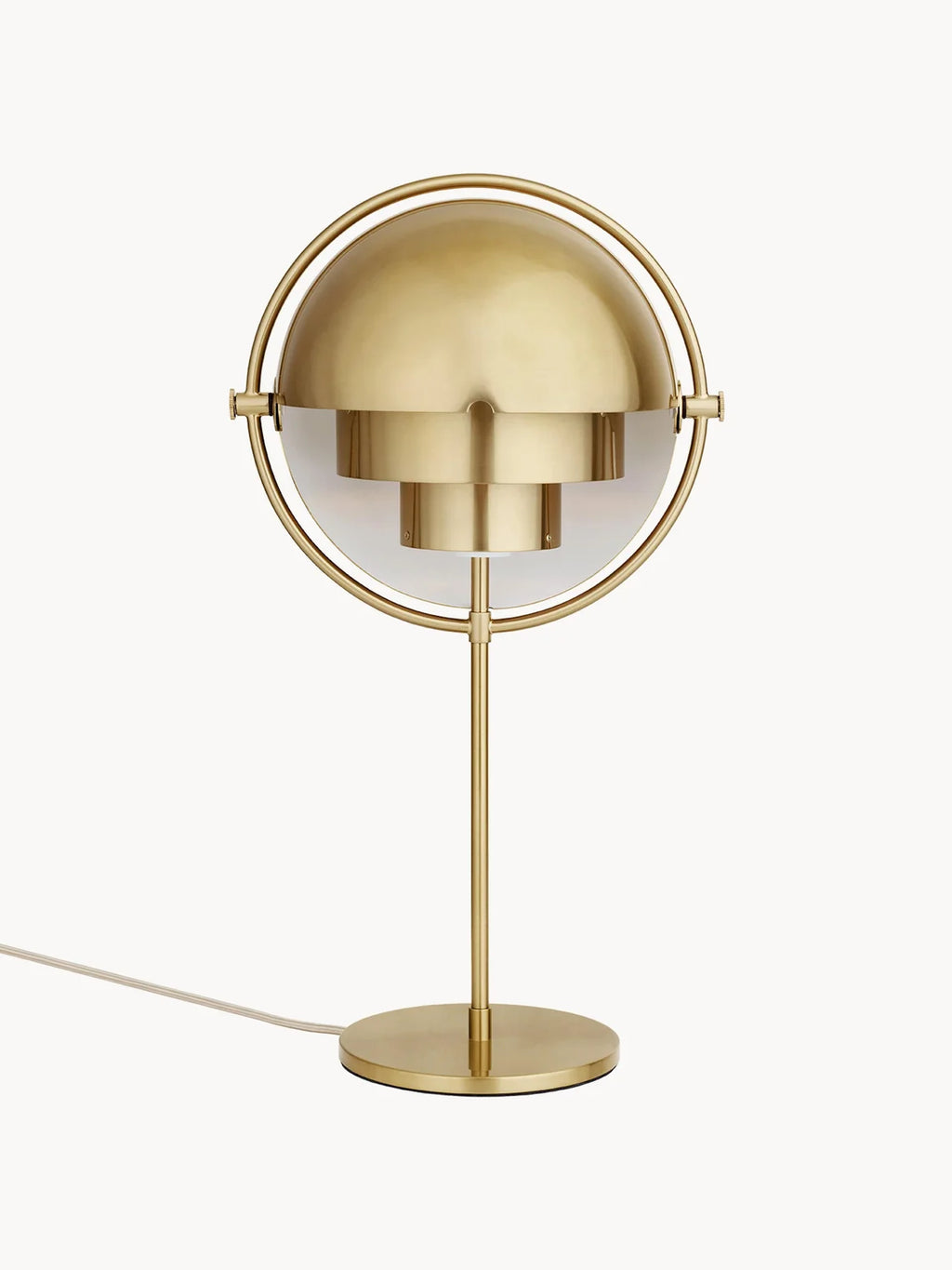 With both quarter-sphere shades rotated closed, the Clérachic table lamp in Brass hoods the inner cylinders so light is aimed down onto the surface.