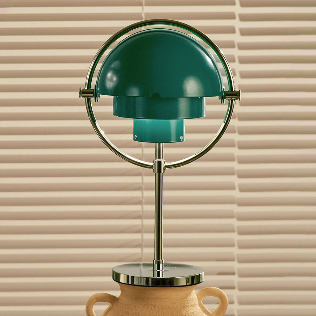 Clérachic rechargeable table lamp in deep green, its chrome ring and moveable shades, standing on a ceramic urn.