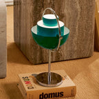 The Clérachic lamp lit on a stack of books, shades opened so warm light spills from the lower bowl.