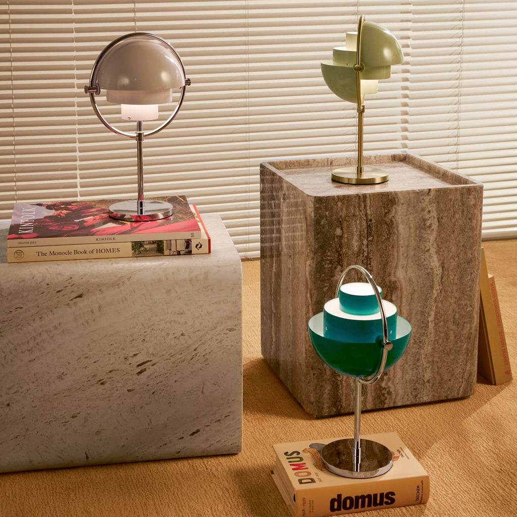 Clérachic lamps in lilac, sand and deep green lit across travertine blocks and stacked books.