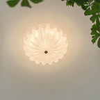 Clérachic Murano-Style Scalloped Glass Flush Ceiling Light viewed straight from below, casting a soft halo across the ceiling by a leafy corner.