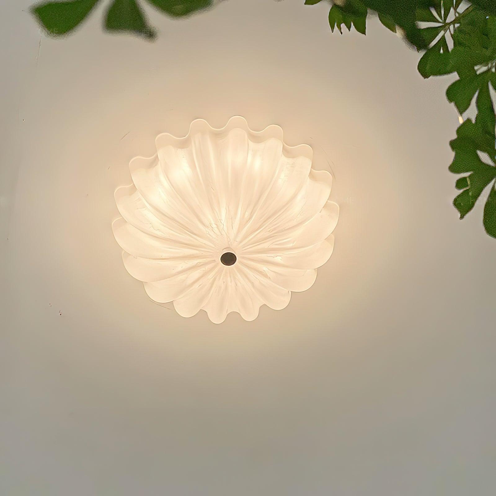 Clérachic Murano-Style Scalloped Glass Flush Ceiling Light viewed straight from below, casting a soft halo across the ceiling by a leafy corner.