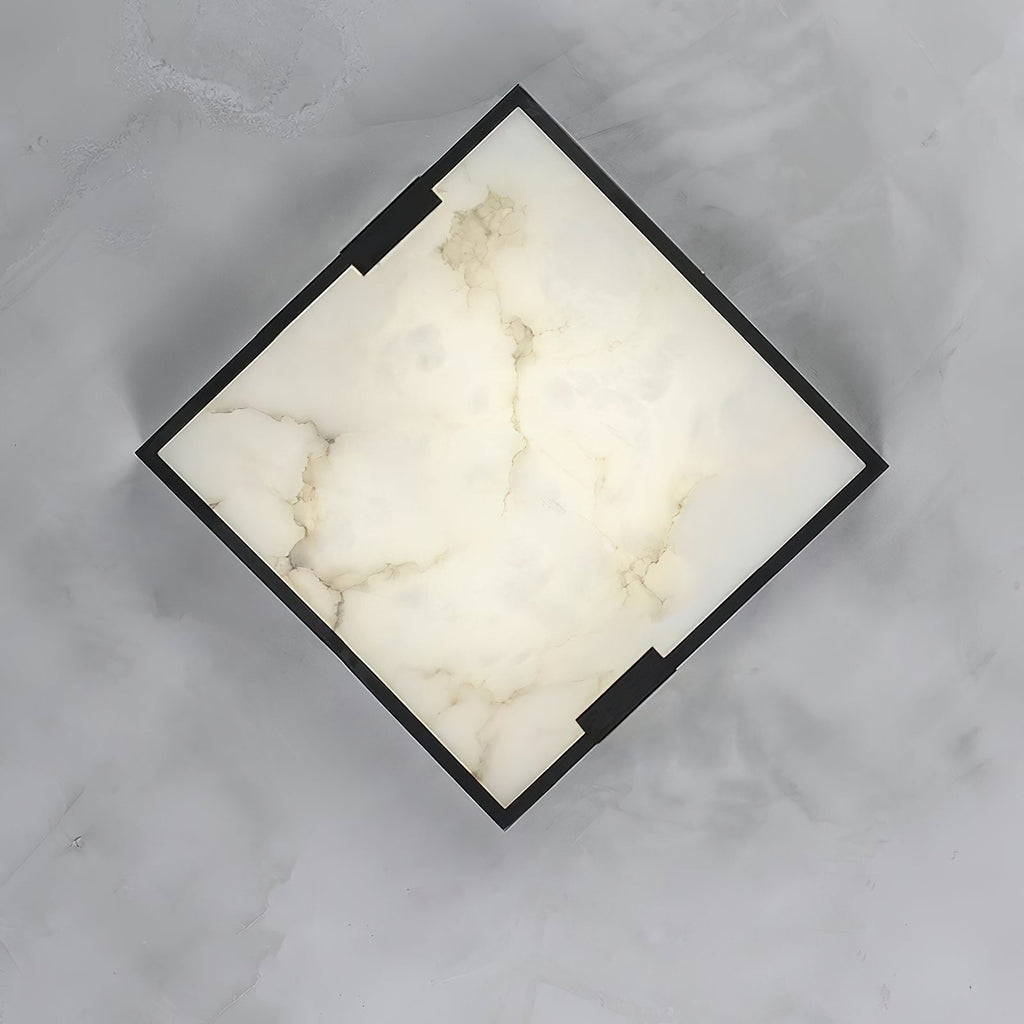 The Clérachic fixture shot straight down on grey stone, its alabaster panel showing natural cloudy veining inside the dark frame.