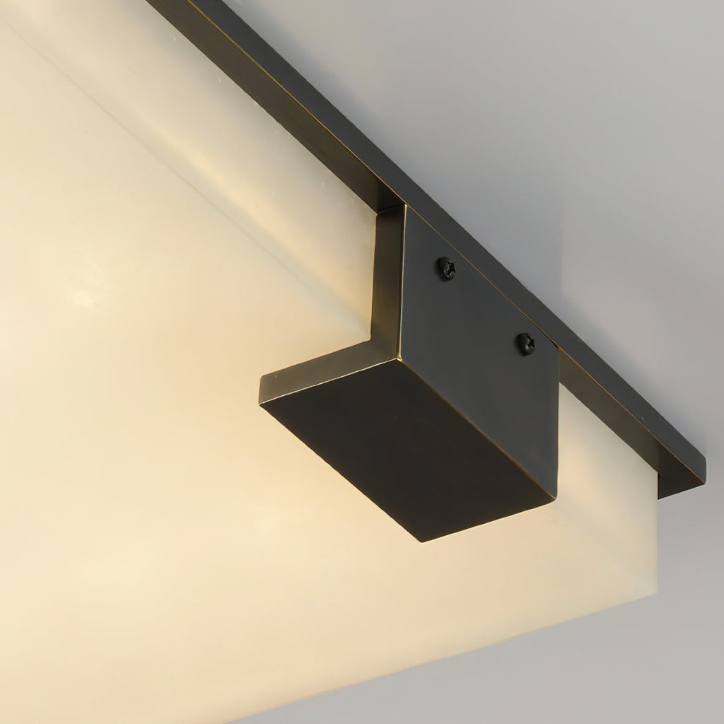 Close view of the Clérachic light's cast bracket, two visible screws anchoring the dark metal arm over glowing alabaster.