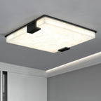 Clérachic ceiling light against a grey ceiling, its marbled alabaster surface lit edge to edge above a cove-lit wall.