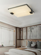 The Clérachic light centred on a bedroom ceiling, its soft glow warming timber-framed windows and an upholstered headboard.