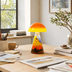 A Clérachic table lamp in the Golden Peaks style on a light desk, with art sketches, a pot of pencils and a ceramic mug.