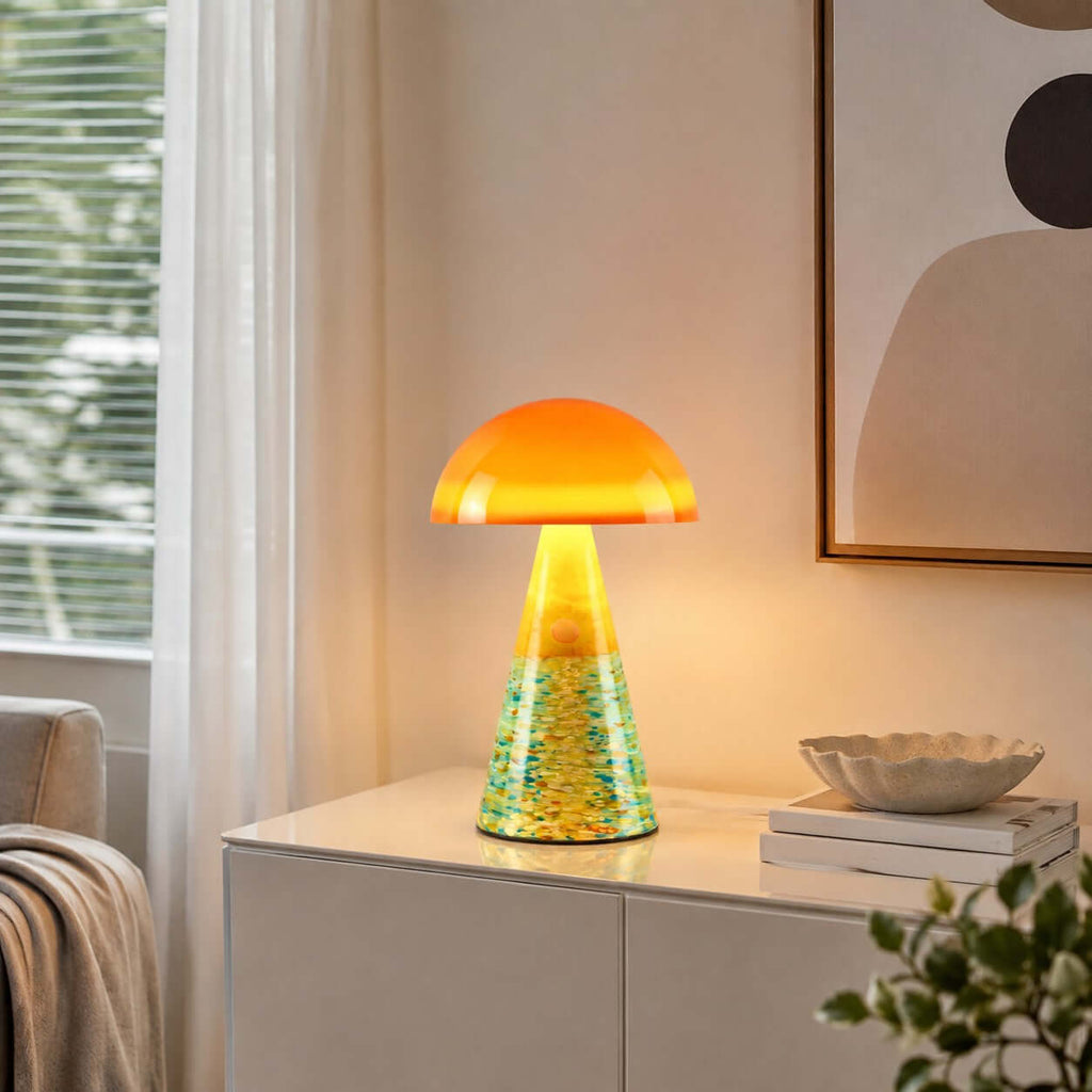 Sunrise Coast Clérachic table lamp lit on a white cabinet, with a green-and-yellow textured base and a shell-shaped dish beside it.
