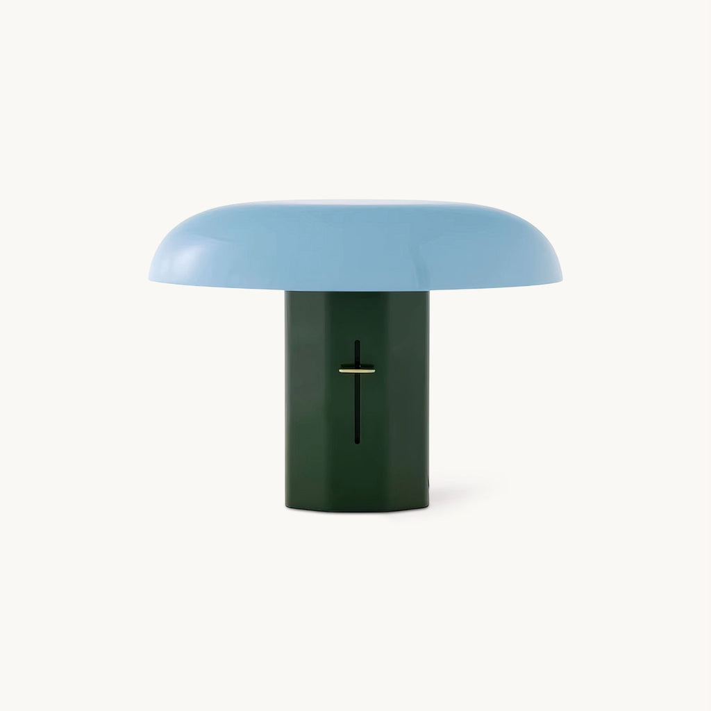 A Clérachic mushroom table lamp with a pale blue dome shade on a dark green column, on a plain white backdrop.