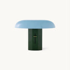 A Clérachic mushroom table lamp with a pale blue dome shade on a dark green column, on a plain white backdrop.