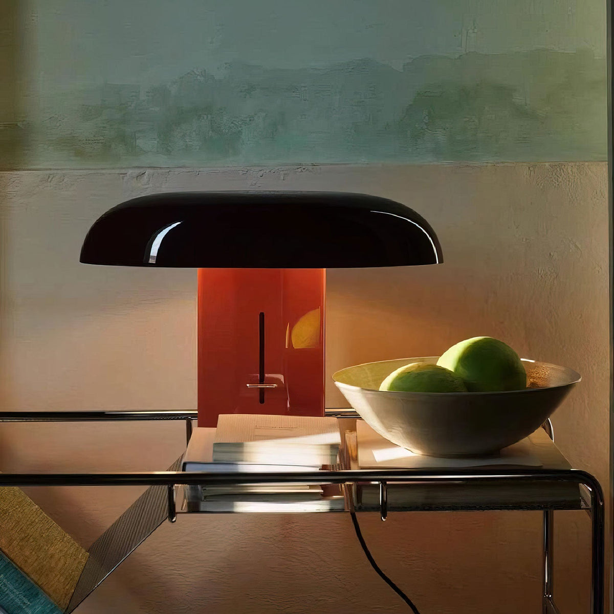 Clérachic table lamp with a dark shade and red-orange column, on a glass side table beside a bowl of green apples.