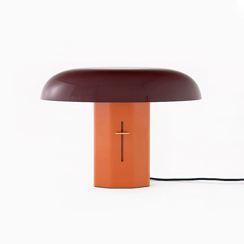 Front view of a Clérachic table lamp with a deep burgundy shade and orange base, its black cord trailing to the right.