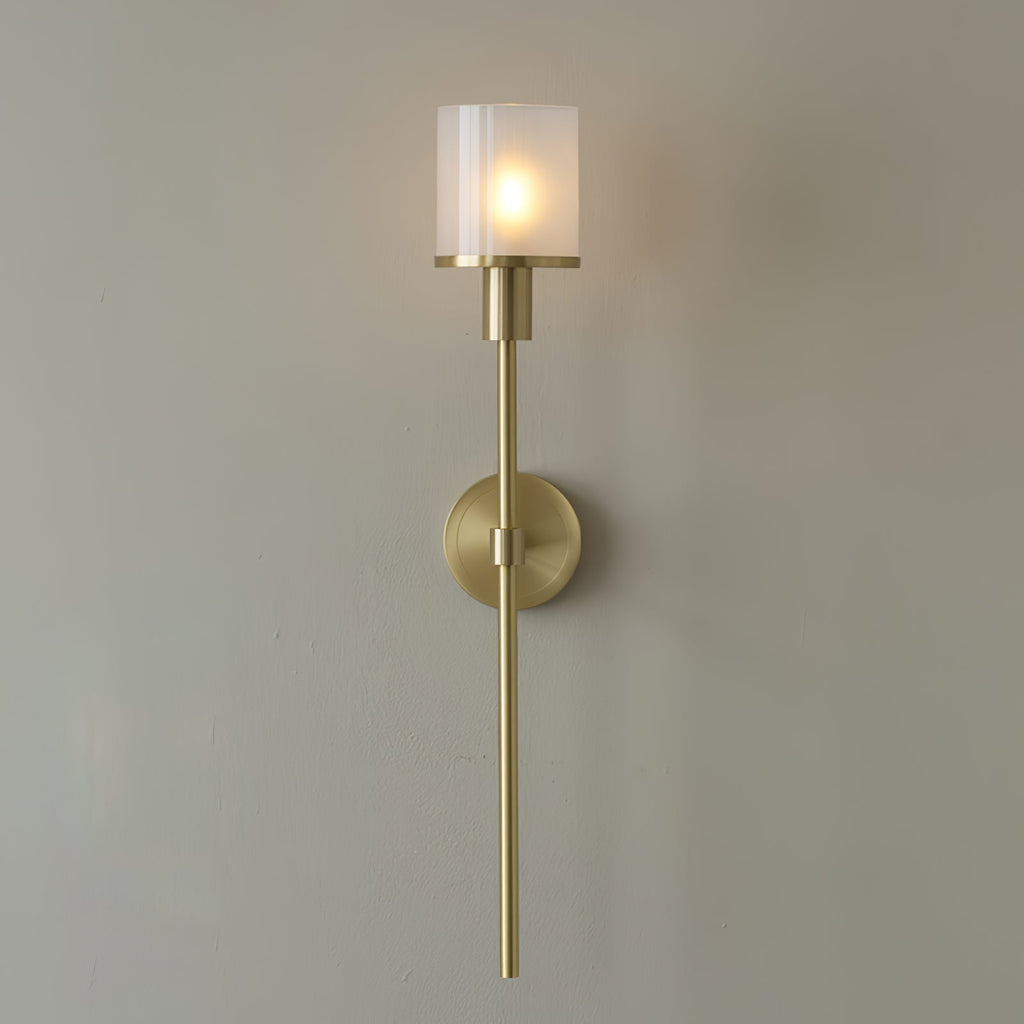 Clérachic Mycara wall sconce in copper, its fluted glass cylinder lit warm above a round backplate and slim stem.