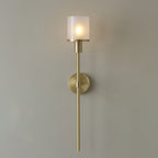 Clérachic Mycara wall sconce in copper, its fluted glass cylinder lit warm above a round backplate and slim stem.