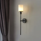 The Clérachic Mycara in black, mounted beside a pleated grey curtain with the glass shade glowing softly.
