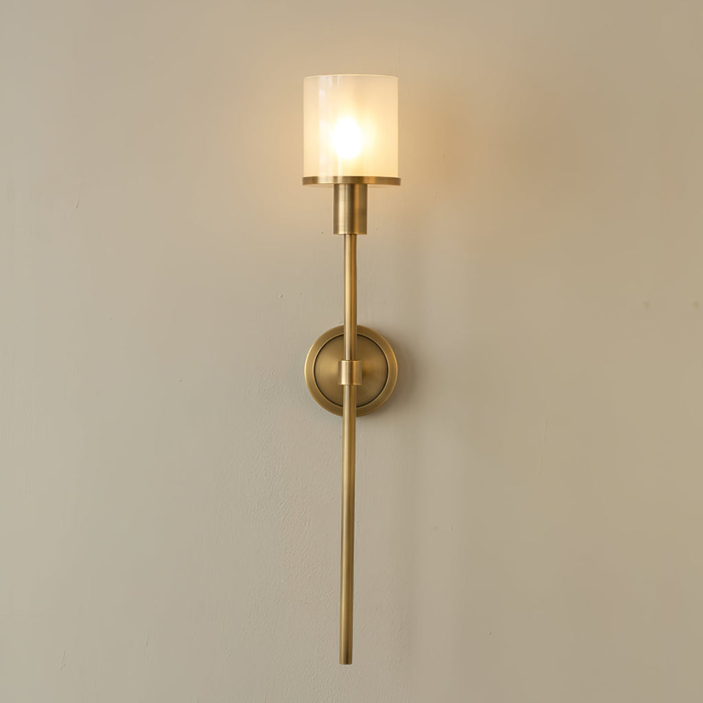 Clérachic Mycara sconce in polished copper, the lit glass shade casting a warm pool across a cream wall.