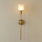 Clérachic Mycara sconce in polished copper, the lit glass shade casting a warm pool across a cream wall.