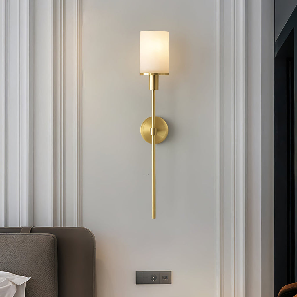 The Clérachic Mycara with its alabaster shade on a panelled bedroom wall, beside a grey upholstered seat.