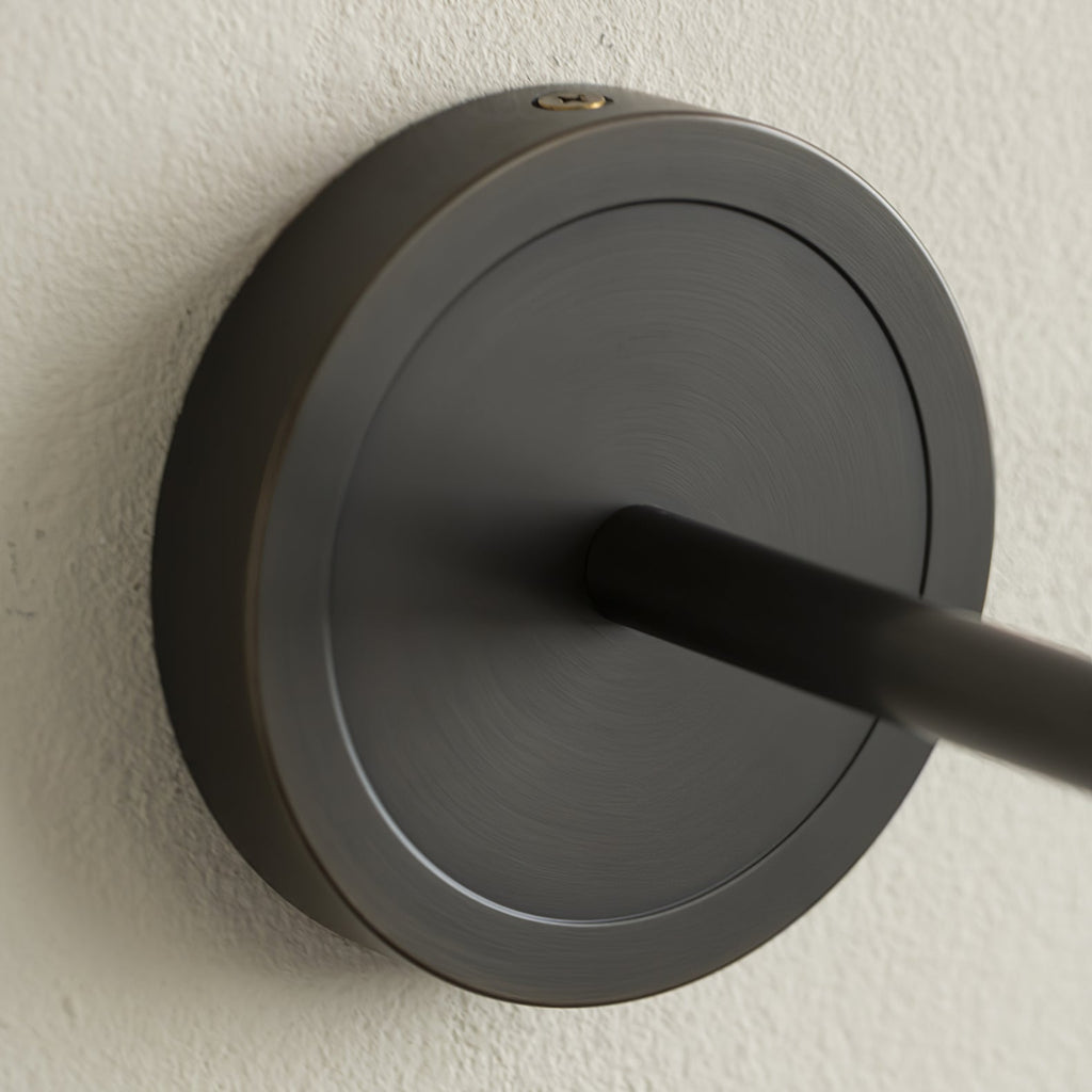 Close view of the Clérachic Mycara's black round backplate, showing the arm joint and top fixing screw.