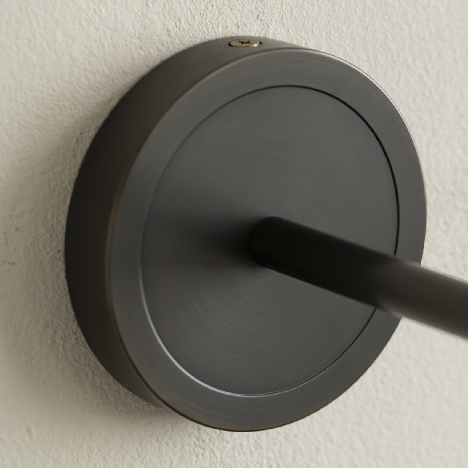 Close view of the Clérachic Mycara's black round backplate, showing the arm joint and top fixing screw.
