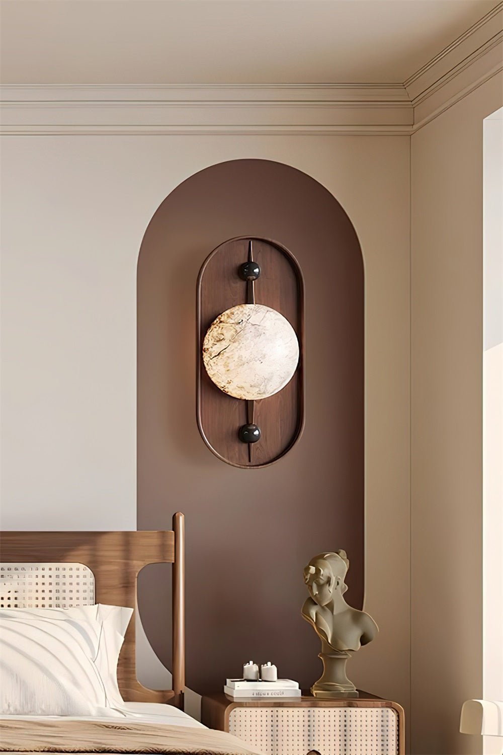 Clérachic mounts the sconce inside a painted arch alcove, lighting a cane bed and a small sculpture on the nightstand.