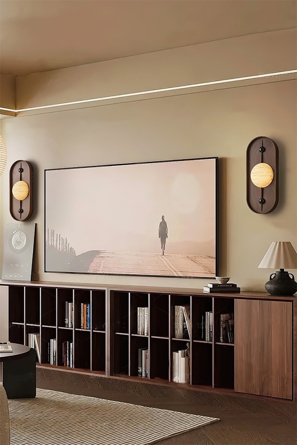 Clérachic sconces flank a wall-mounted screen in a matched pair, above a long walnut bookcase console.