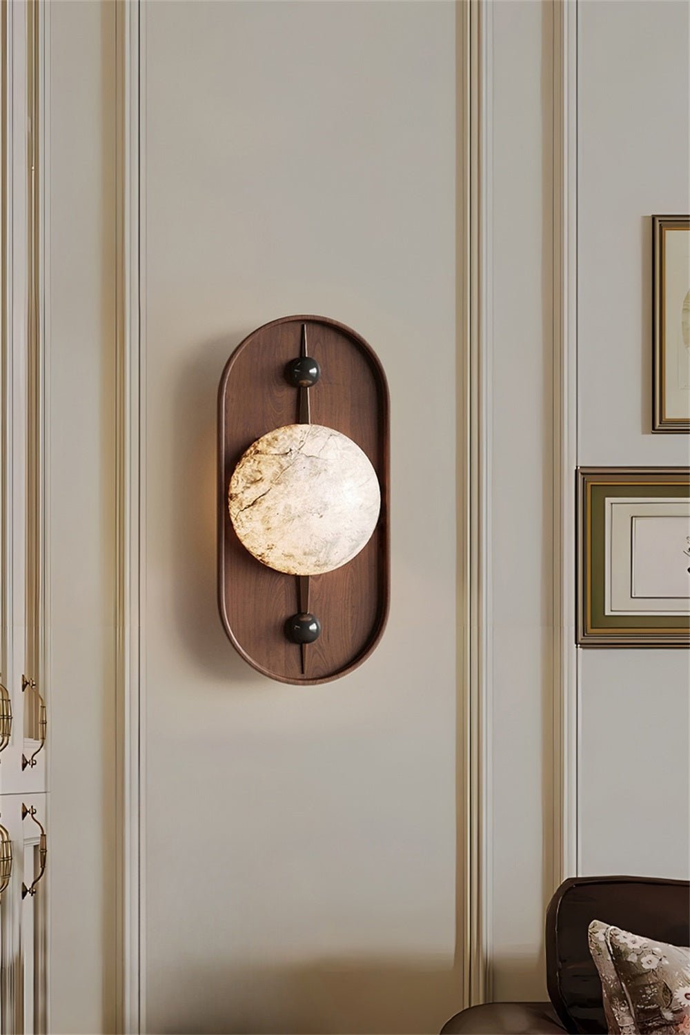 Clérachic hangs the wall light on a panelled hallway, its warm glow catching the gilt frames alongside it.