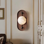 The Clérachic sconce closer on the panelled wall, lighting the moulding and the framed prints hung beside it.