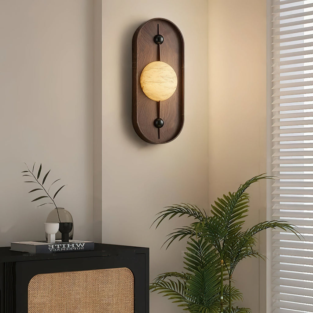 Clérachic lights a quiet corner, the orb glowing above a black and rattan cabinet with a potted palm alongside.