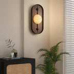 Clérachic lights a quiet corner, the orb glowing above a black and rattan cabinet with a potted palm alongside.