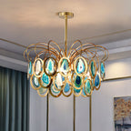 The blue version of this Clérachic chandelier lit in a room with teal curtains, brass trim and a framed landscape on the wall.