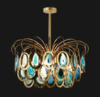 Blue agate Clérachic chandelier on a black backdrop, the glowing teal slices set in polished gold rings under looping brass wires.
