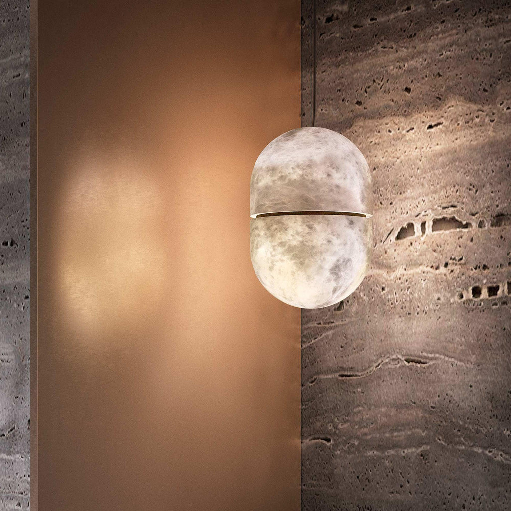 This Clérachic alabaster pendant glowing softly against a copper-toned wall and a rough travertine slab.