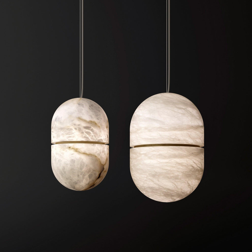 Two Clérachic alabaster capsules of different sizes on a black backdrop, their veined stone lit softly from within.