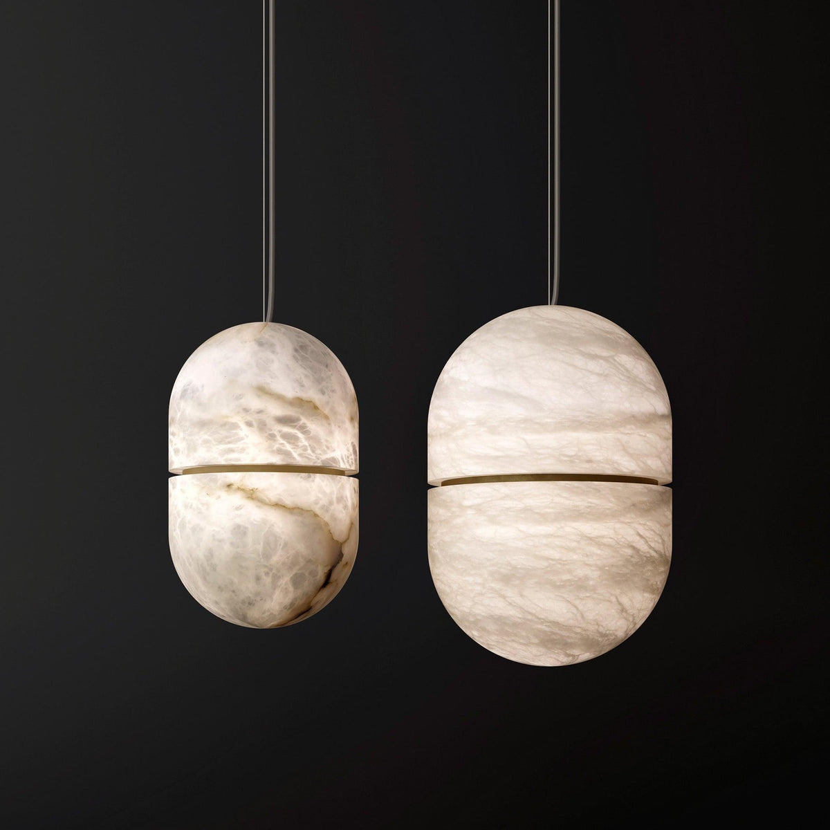 Two Clérachic alabaster capsules of different sizes on a black backdrop, their veined stone lit softly from within.