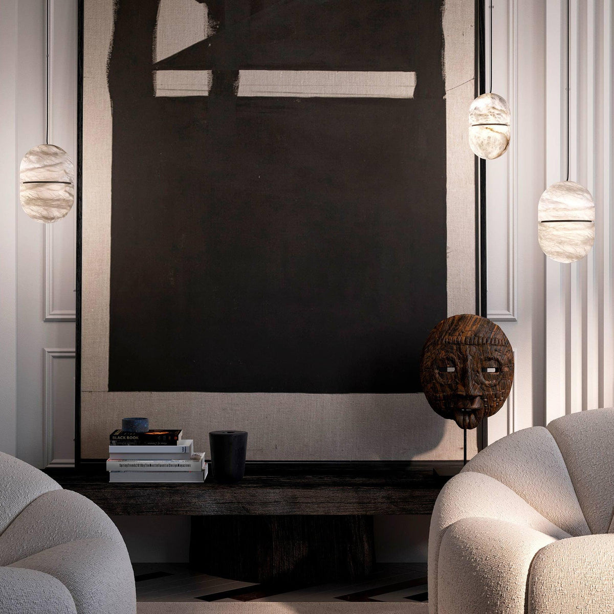 Three Clérachic alabaster pendants floating around a large dark artwork, with a carved wooden mask and two boucle armchairs below.
