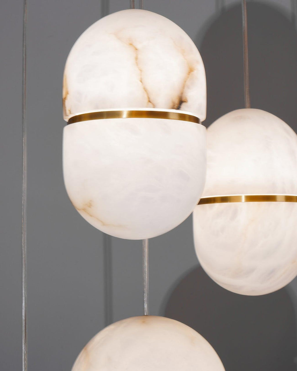 Close view of three Clérachic alabaster pendants, with the gold band and the dark veins in the stone clearly visible.