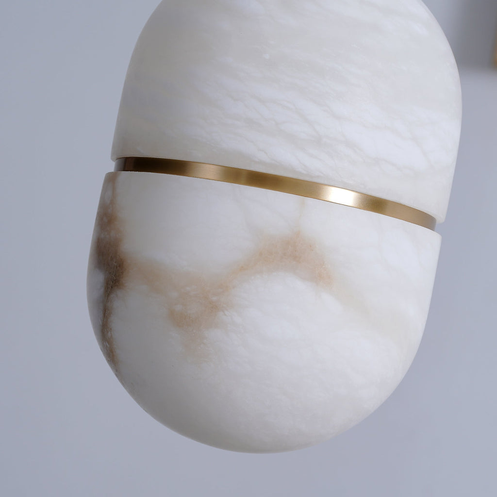 Close view of the veining and the slim gold band on this Clérachic alabaster pendant, with brown streaks through the white stone.